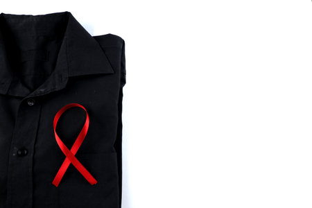 Red ribbon on a black shirt on a white background. Modern treatment and healthcare. AIDS awareness conceptの写真素材