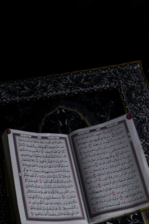 Al-Quran which is above the prayer rug with a black background