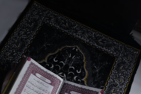 Al-Quran which is above the prayer rug with a black backgroundの写真素材