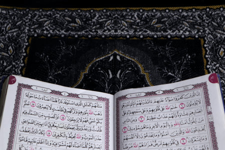 Al-Quran which is above the prayer rug with a black backgroundの写真素材