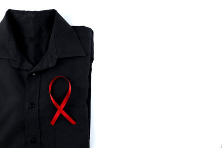 Red ribbon on a black shirt on a white background. Modern treatment and healthcare. AIDS awareness concept.の写真素材