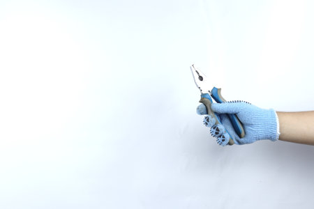 Gloved hand holding pliers isolated on white backgroundの写真素材