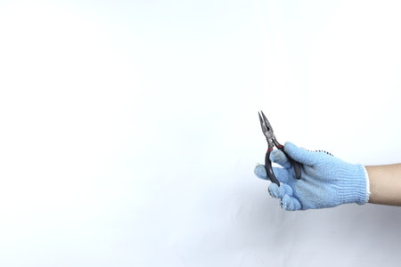 Gloved hand holding pliers isolated on white backgroundの写真素材