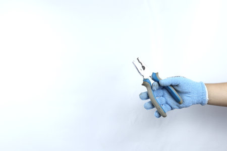 Gloved hand holding pliers isolated on white backgroundの写真素材
