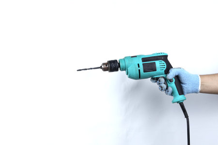 Gloved hand holding electric drill isolated on white backgroundの写真素材