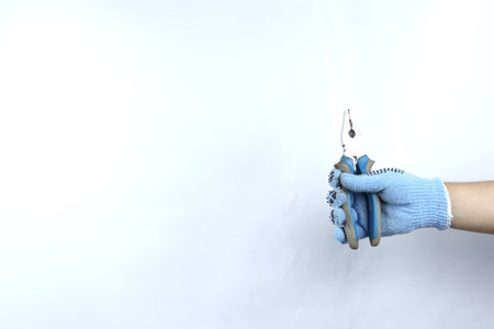 Gloved hand holding pliers isolated on white backgroundの写真素材