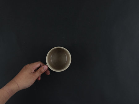 hand holding ceramic mug isolated on black backgroundの写真素材