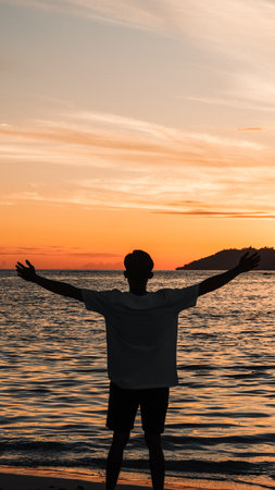 Silhouette of a Man Standing on the Beach at Sunriseの写真素材