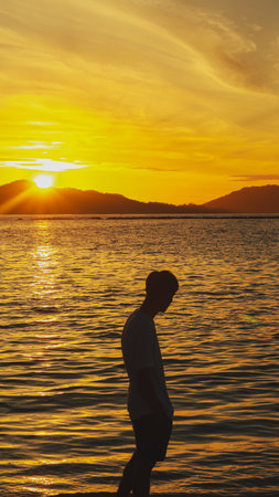 Silhouette of a Man Standing on the Beach at Sunriseの写真素材