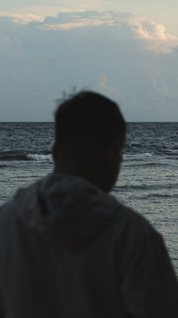 Silhouette of a man looking at the sea in the evening