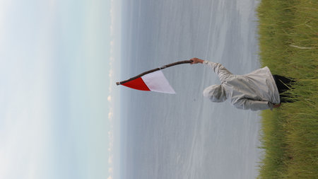 A man waving the Indonesian flag at the top of Dunu Hill, Gorontalo-Indonesiaの写真素材