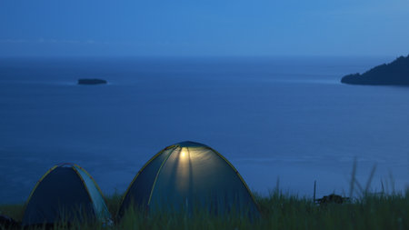 Camping tent on a hill with sea and sky backgroundの写真素材