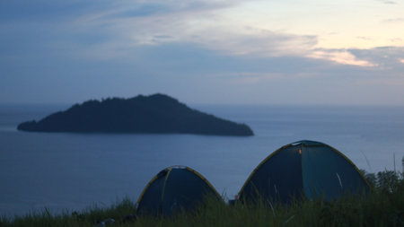 Camping tent on a hill with sea and sky backgroundの写真素材