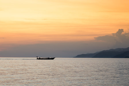 Silhouette of a fishing boat in the sea at sunset.の写真素材