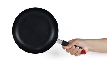 Hand holding a black frying pan isolated on white background, clipping path includedの写真素材