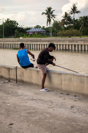 Unidentified men are fishing in the river.の写真素材