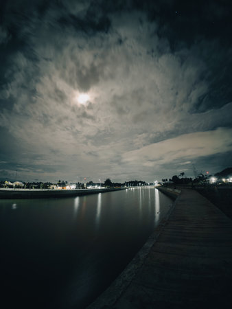 Night view of the river with dark clouds and the moon on the skyの写真素材