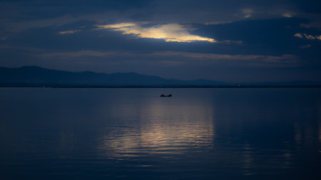 Tranquil Lake with Boat at Sunsetの写真素材