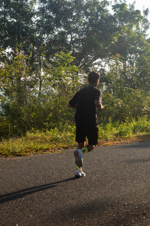Man Jogging on Road Surrounded by Trees