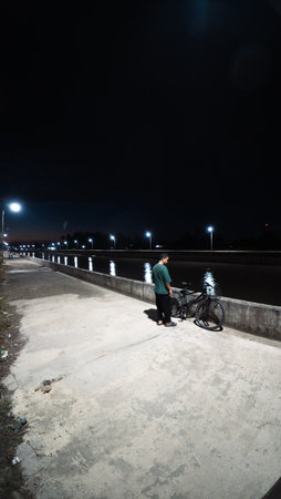 Man Standing with Bike at Nightの写真素材