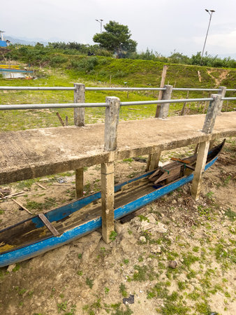 Rustic Blue Boat Under a Concrete Bridge by a Dry Shoreの写真素材