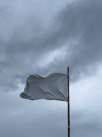 Torn White Flag Against Overcast Skyの写真素材