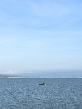 Lone Boat on Calm Blue Waters Under a Clear Skyの写真素材