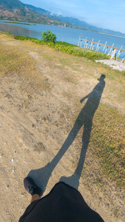 Long Shadow of Person Walking on Shoreの写真素材