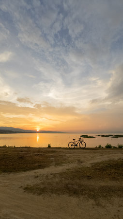 Bicycle Parked By Lake at Sunsetの写真素材