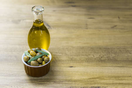 Fresh and organic green olives in a small red bowl together with olive oil in a bottleの写真素材