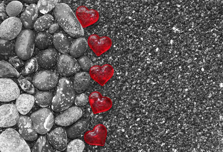 Glass hearts on the beautiful black and white sands of the beachの写真素材