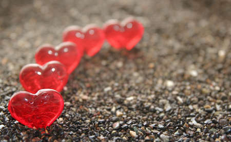 Glass hearts on a background of sea sandの写真素材