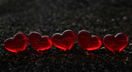 Glass hearts sitting in the black sands of the seaの写真素材