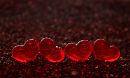 Glass hearts sitting in the sands of the seaの写真素材