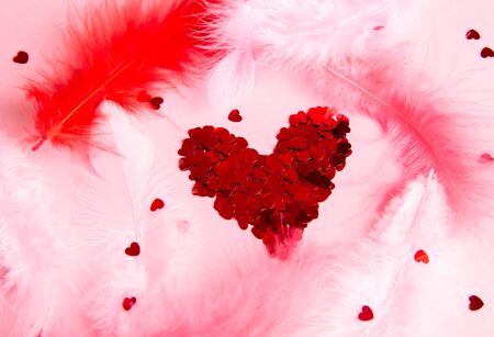 confetti heart on a pink background with feathersの写真素材