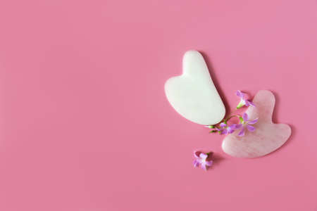 Modern accessories for self-facial massage. Flat lay style. Pink background.