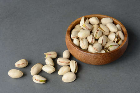 Pistachios in a wooden cup, close-up on a dark concrete background. Copy space for text.の写真素材