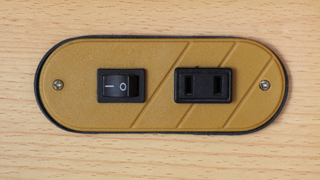 black plug socket on brown wood backgroundの写真素材
