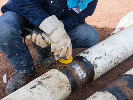 Man is grinding on a support after welding the piece in place の写真素材