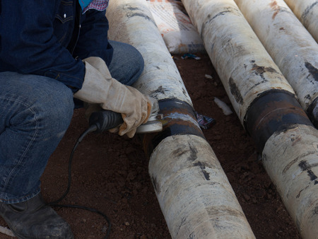 Man is grinding on a support after welding the piece in place 