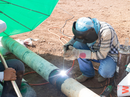 Welder with sparks arcing project Fire hose outdoors 