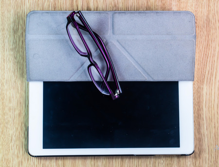 white Tablet with glass on  wooden table 