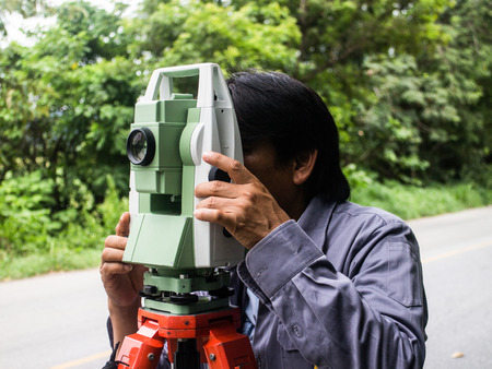 Portrait of builder worker with theodolite transit equipment at construction site outdoors during surveyor workのeditorial素材