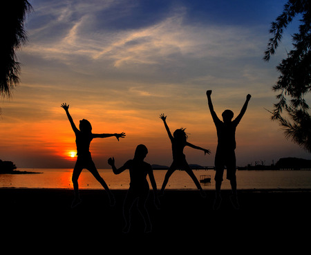 Silhouette of Young People Jumping at Sunsetの写真素材