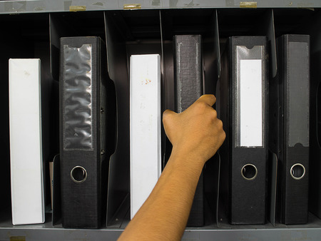 hand catch File folders standing on the shelves at office