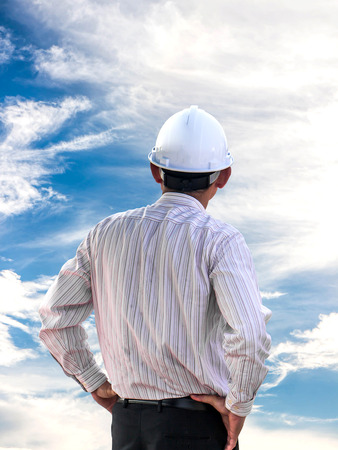 Young engineer looking work in front of skyの写真素材