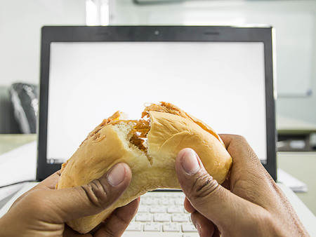 Close up work desk with a computer, Handle eating while working.の写真素材