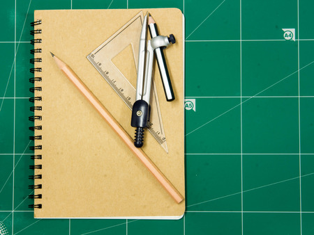 notebook with a pencil on green background