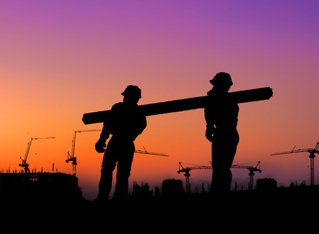 The group of workers working over blurred construction site.の写真素材