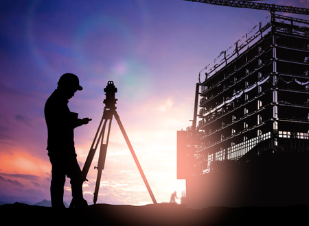 silhouette survey engineer working  in a building site over Blurred construction worker on construction siteの写真素材